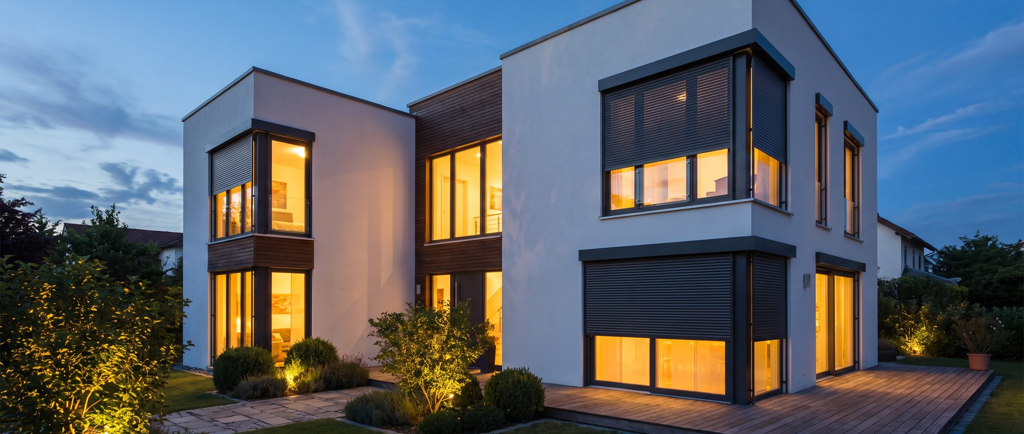 Modernes Wohnhaus zur blauen Stunde mit teils heruntergelassenen Rollläden
